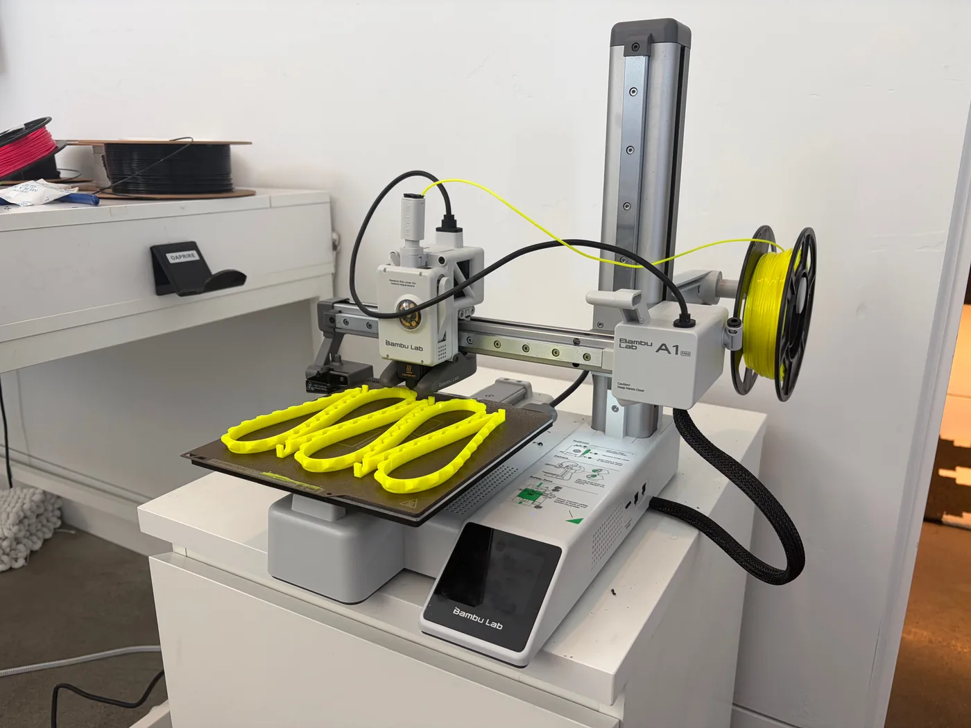 Bambu Lab A1 Mini printing several bright yellow TPU parts on one build plate