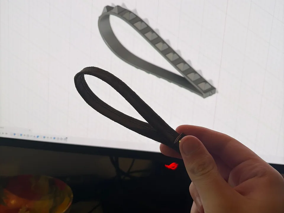 Black printed wrist straps held in front of their Autodesk Fusion CAD model