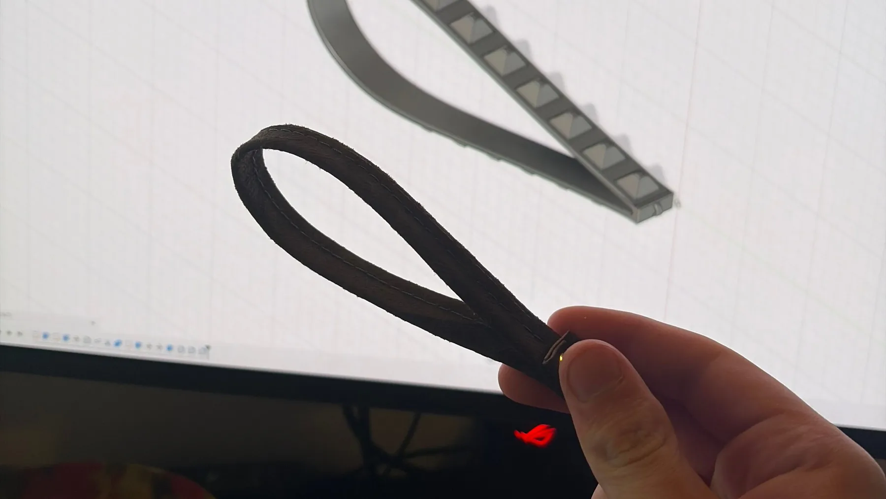 Black printed wrist straps held in front of their Autodesk Fusion CAD model