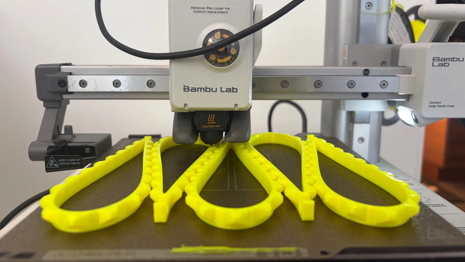 Bambu Lab A1 Mini printing a batch of bright yellow flexible TPU wrist straps