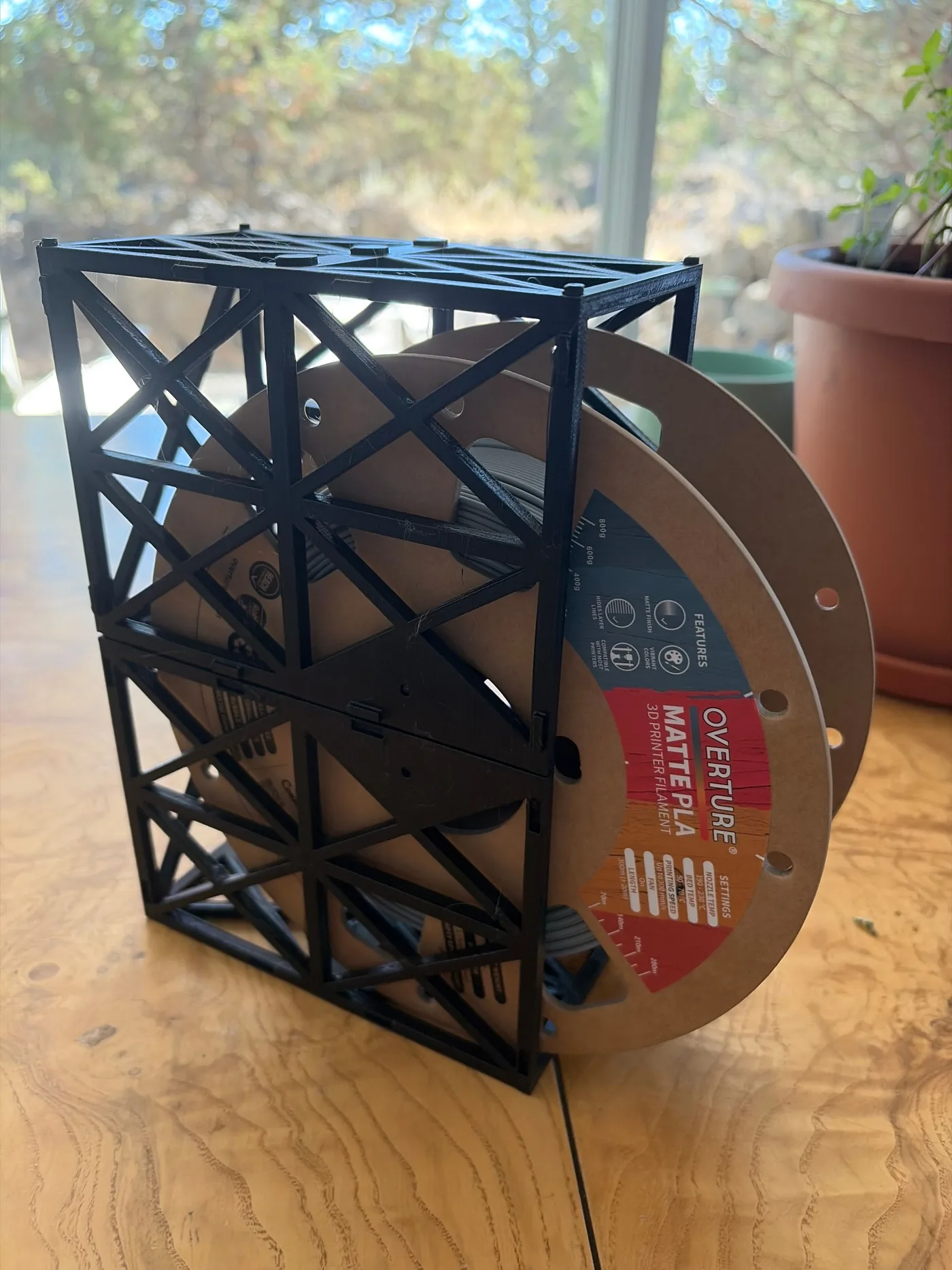 Early black 3D printed filament spool holder supporting a filament spool