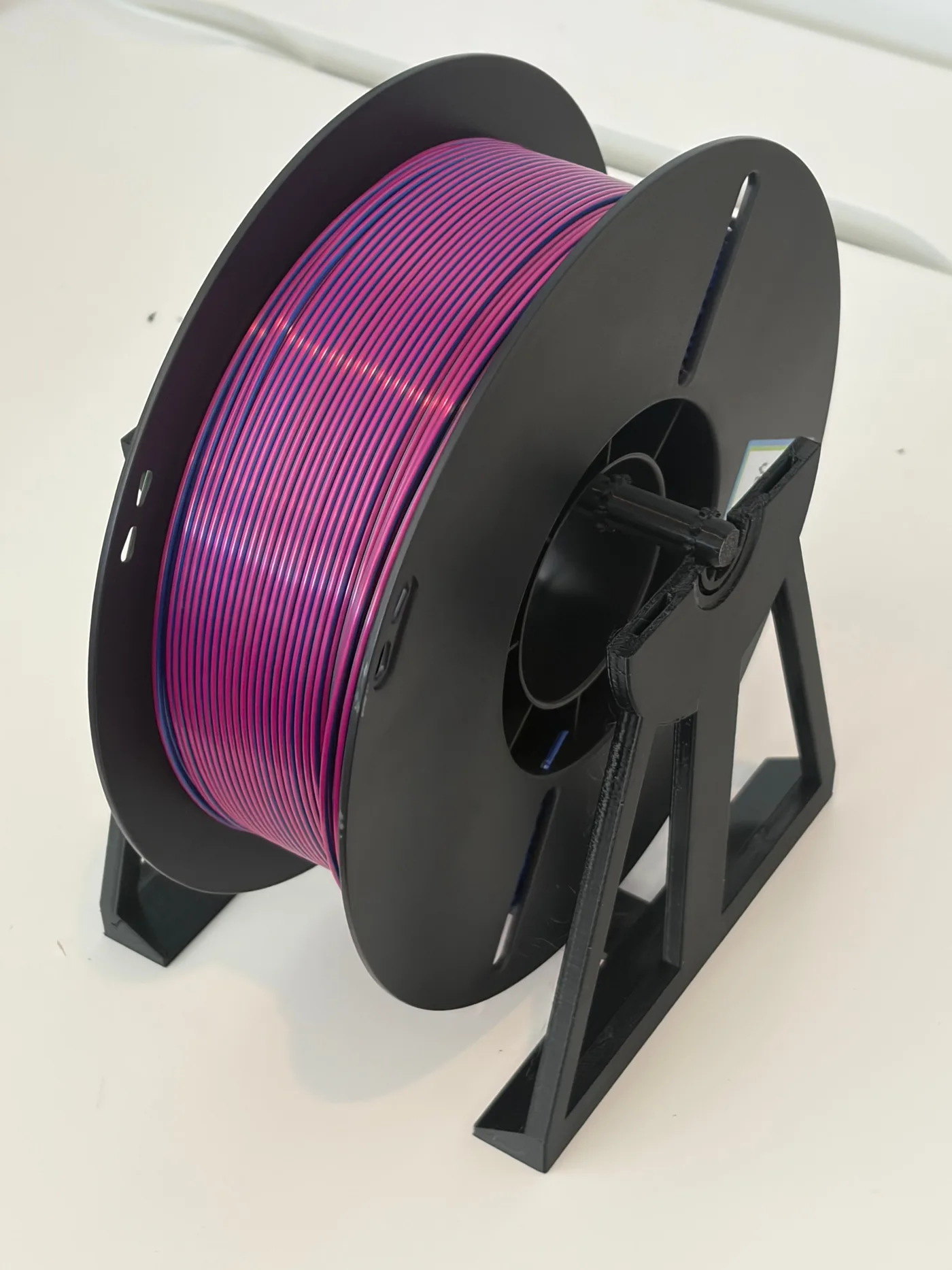 Purple filament spool mounted on a revised black 3D printed spool holder