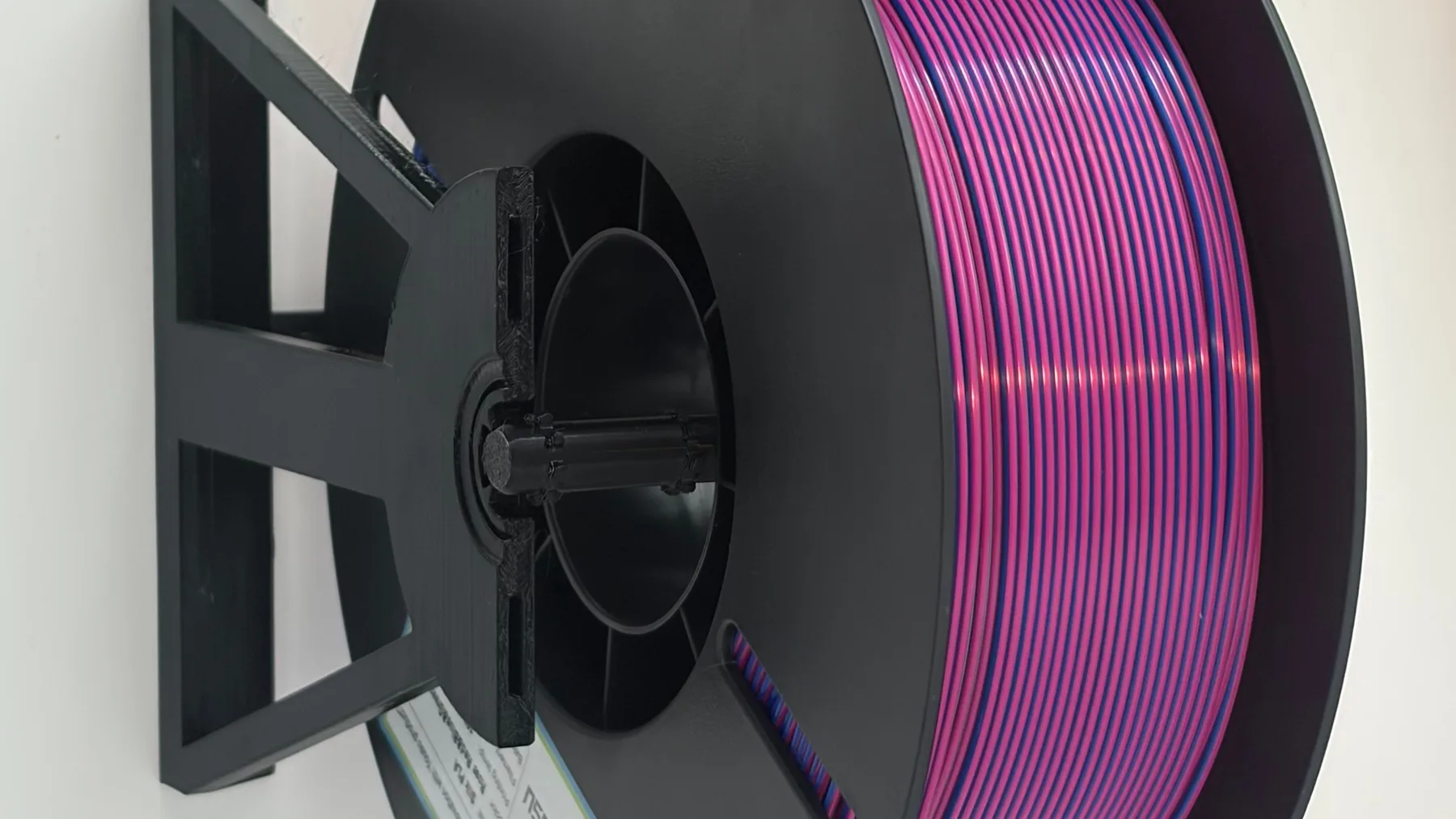 Purple filament spool mounted horizontally in a black 3D printed modular spool holder