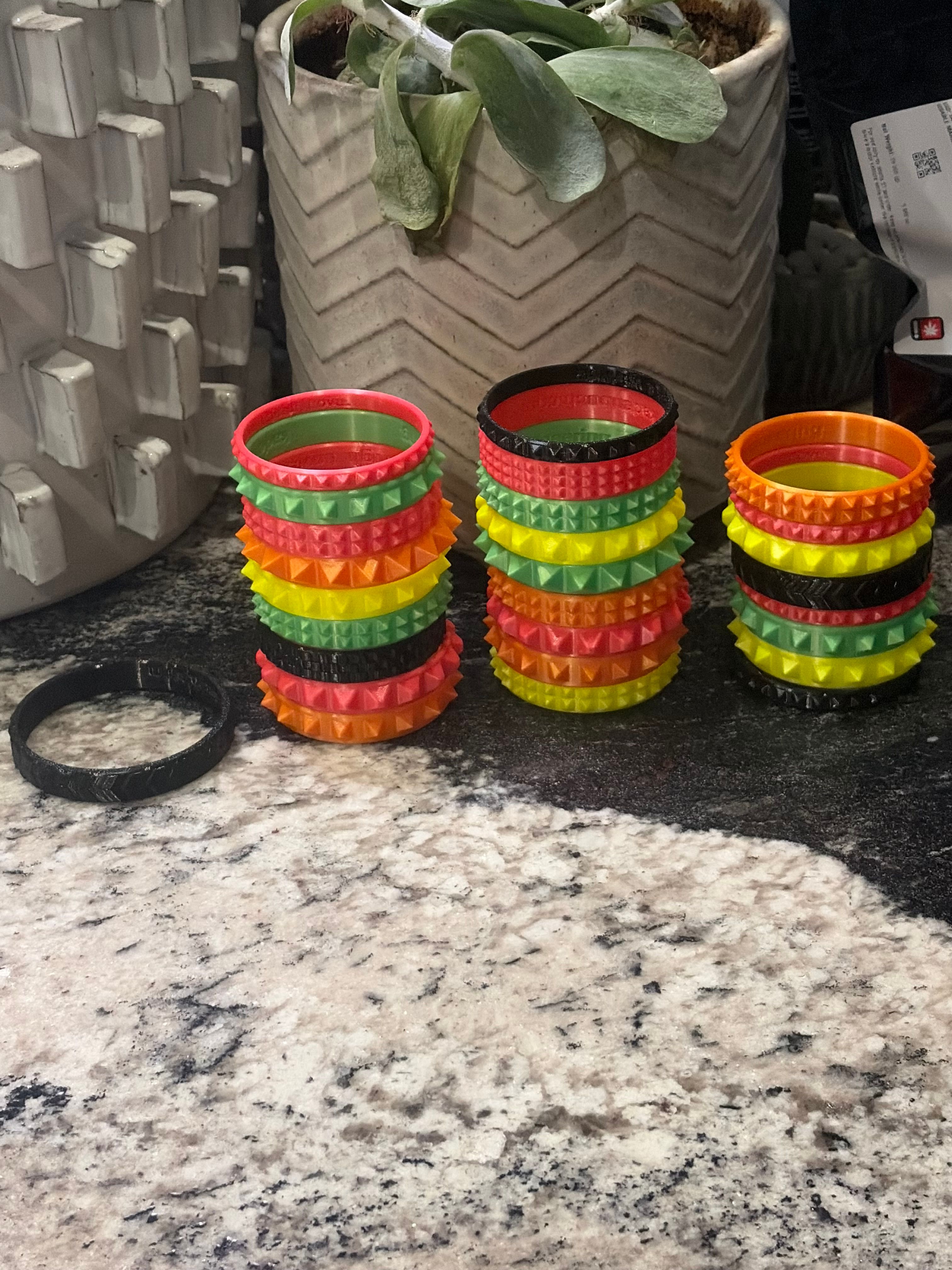 Multiple colorful 3D printed flexible bracelets arranged in rows