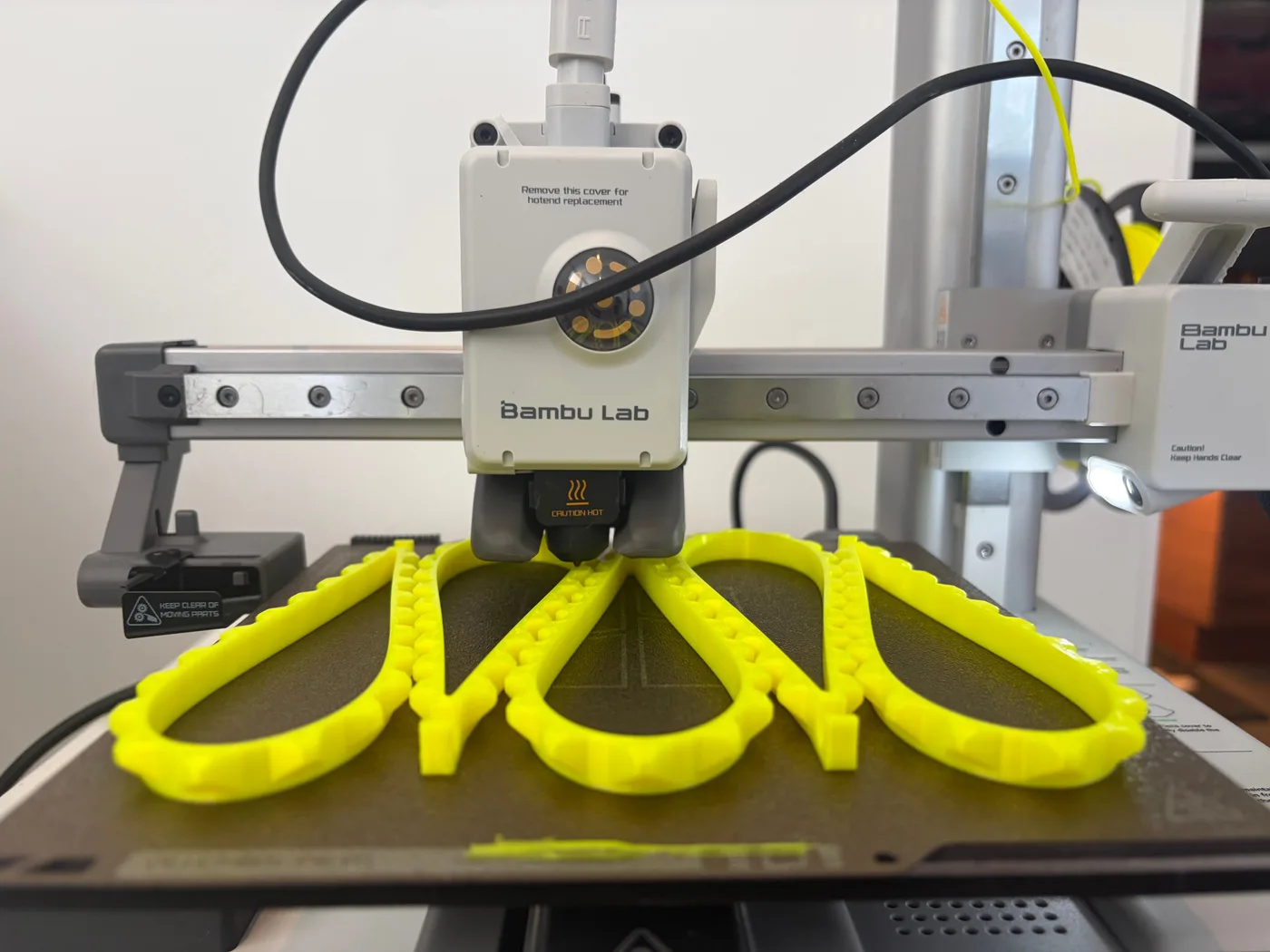 Bambu Lab A1 Mini printing several bright yellow flexible TPU wrist straps
