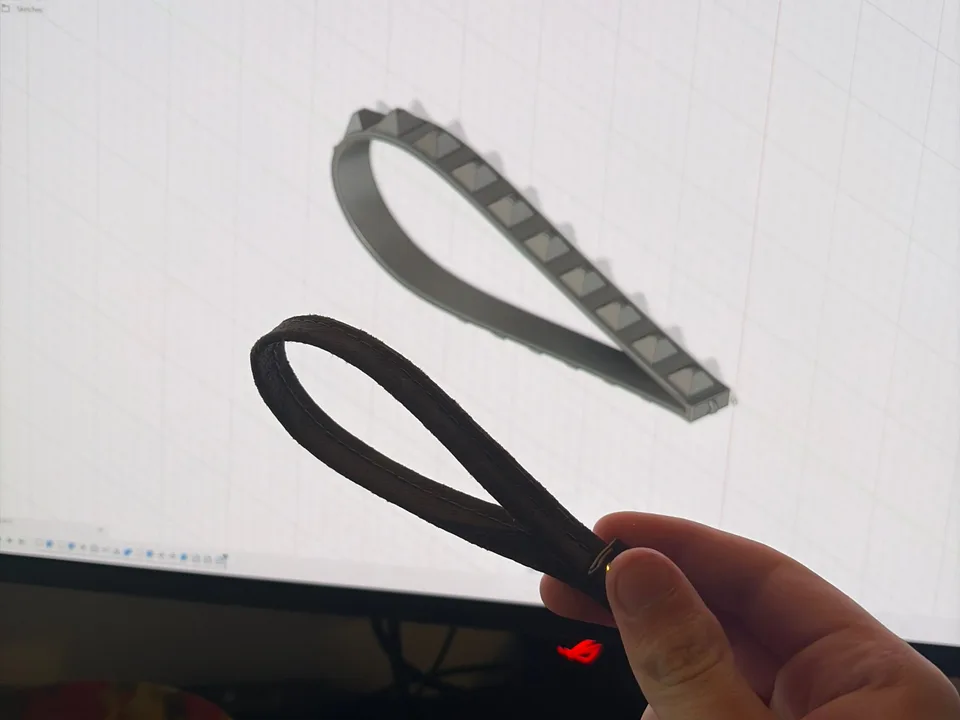 Black printed TPU wrist straps held in front of their Autodesk Fusion CAD model