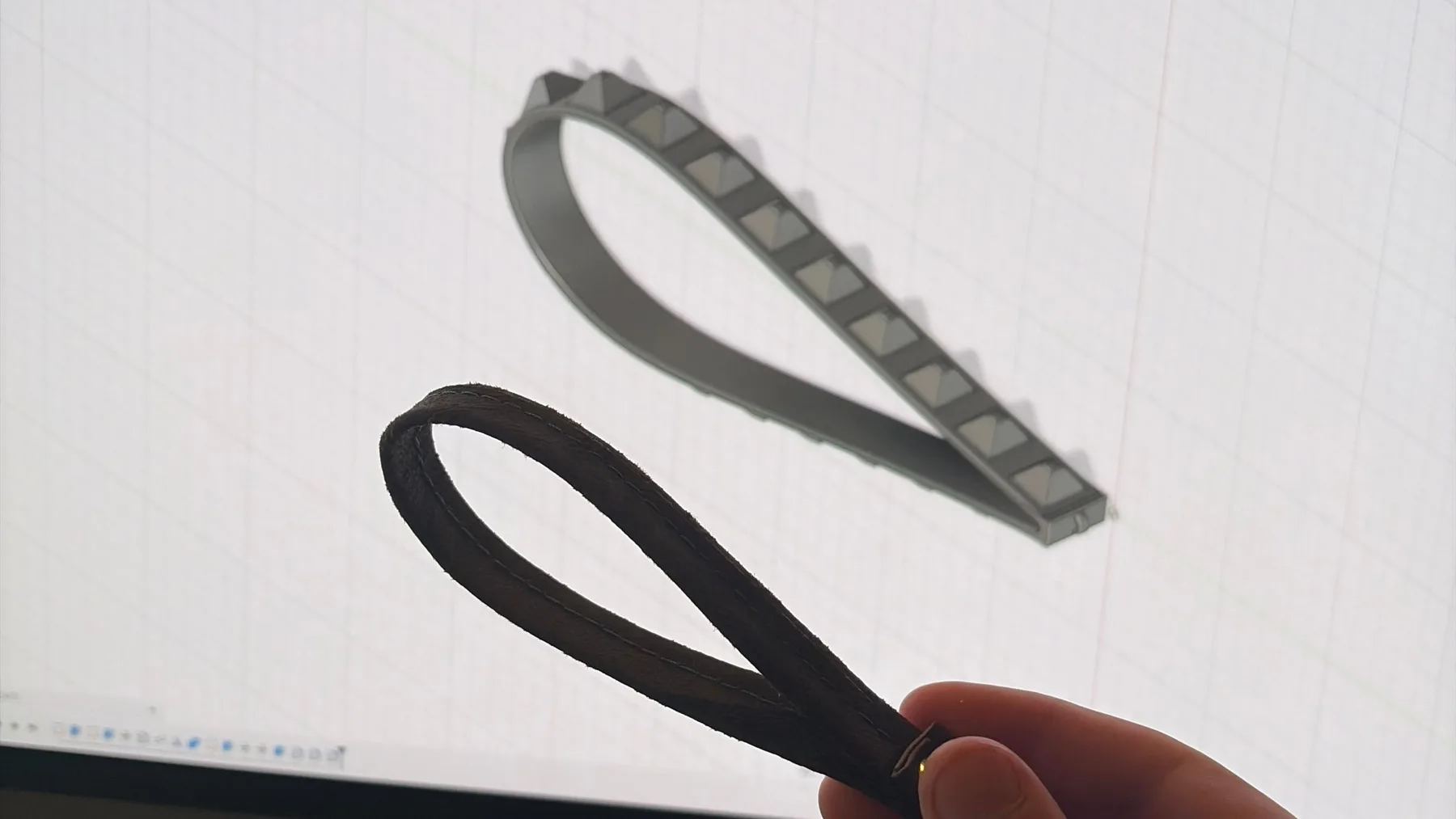 Black printed TPU wrist straps held in front of their Autodesk Fusion CAD model