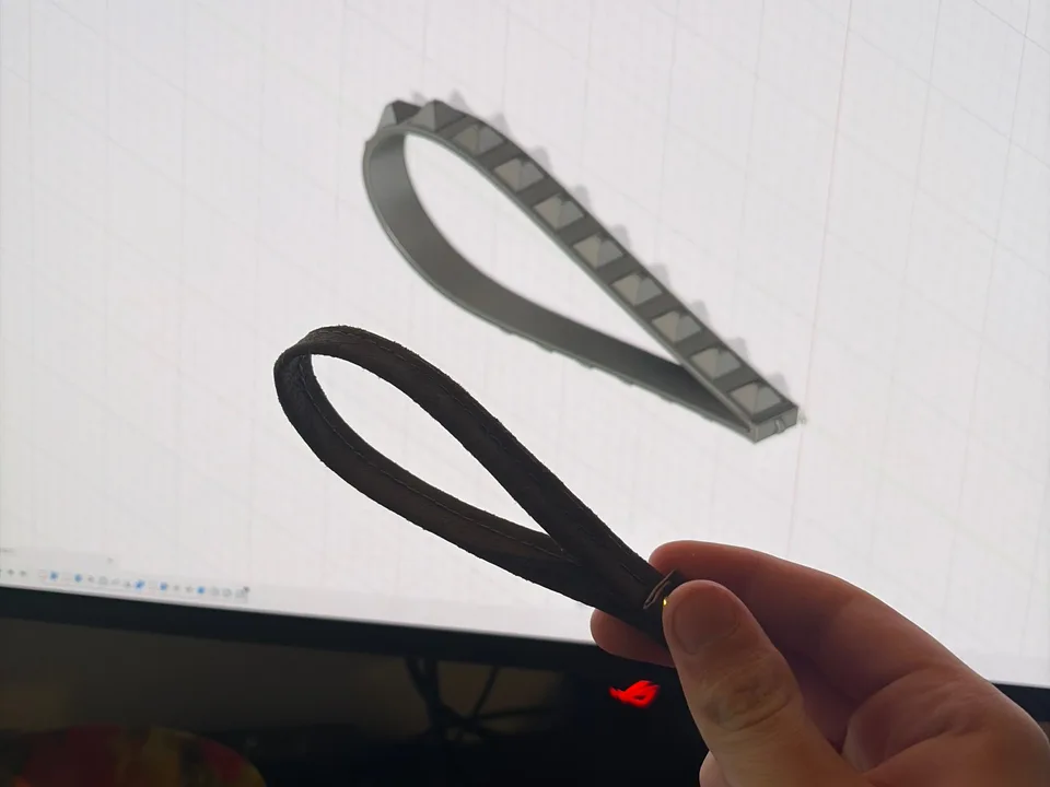 Printed flexible wrist straps held in front of their Autodesk Fusion CAD model